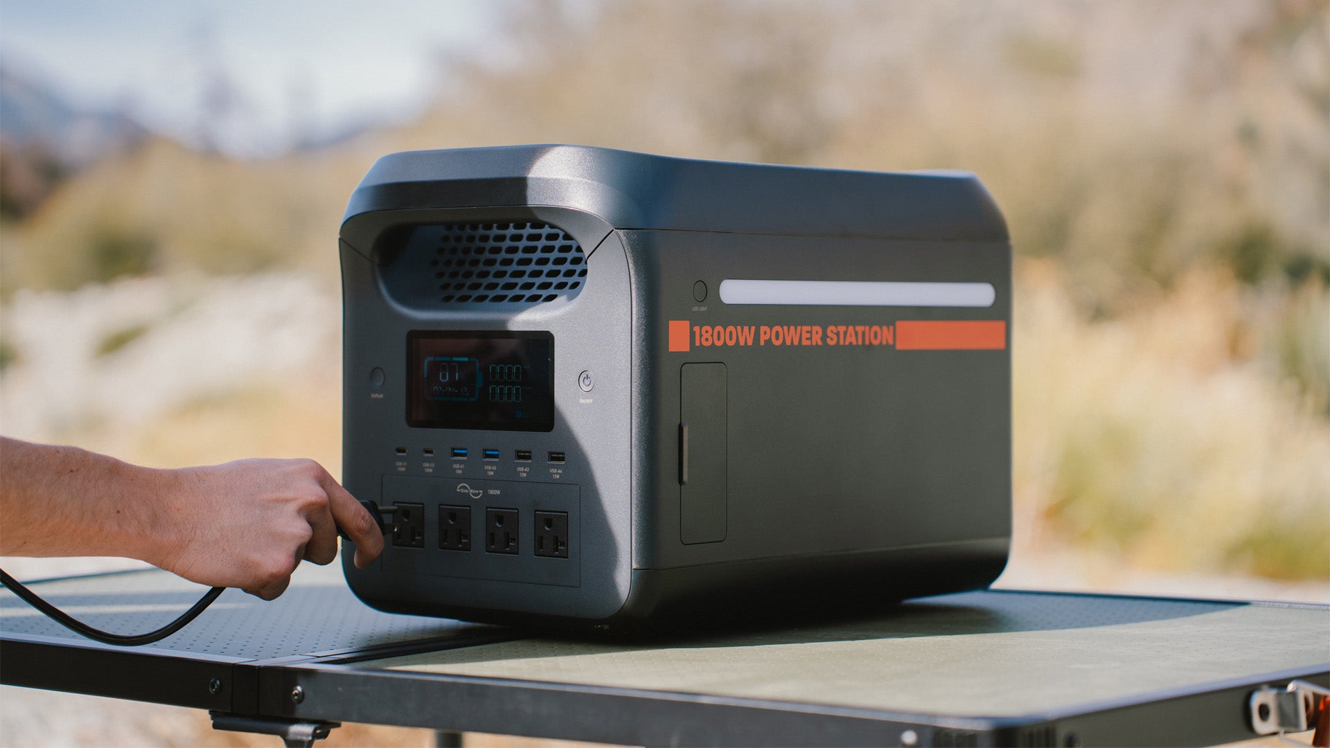 1800W portable power station on table with cord being plugged into it.