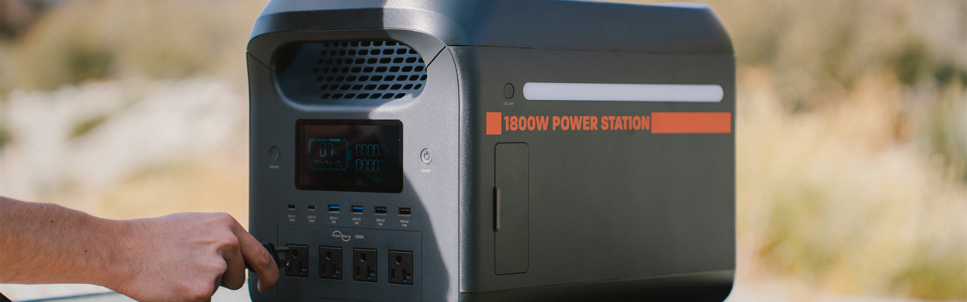 1800W portable power station on table with cord being plugged into it. 